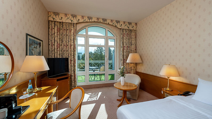 Superior single room with bed, desk, large window, balcony view and classic interior design.