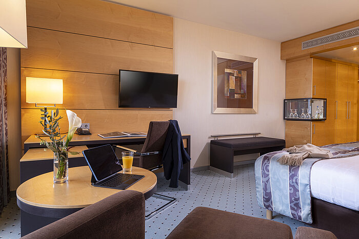 Chambre confort au Maritim Hotel Düsseldorf avec bureau, TV à écran plat, fauteuil confortable et décoration élégante.