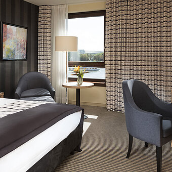 Habitación doble moderna en el Maritim Hotel Königswinter con vistas al Rin y mobiliario elegante.