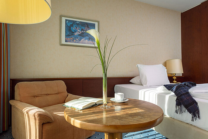 Camera Comfort al Maritim Hotel Colonia con poltrona accogliente, tavolino, letto singolo e elementi decorativi moderni.