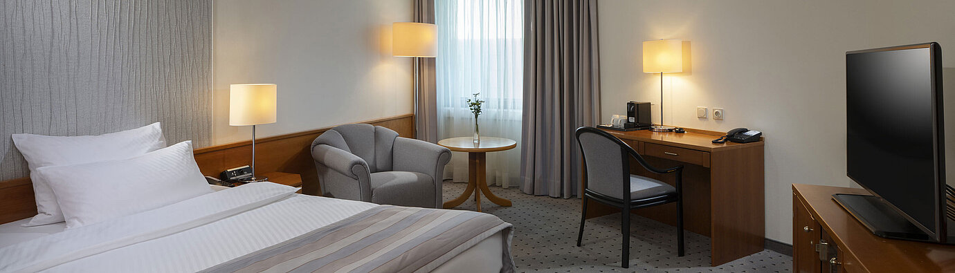 Camera Superior spaziosa con letto, scrivania, TV e illuminazione calda al Maritim Hotel Hannover.