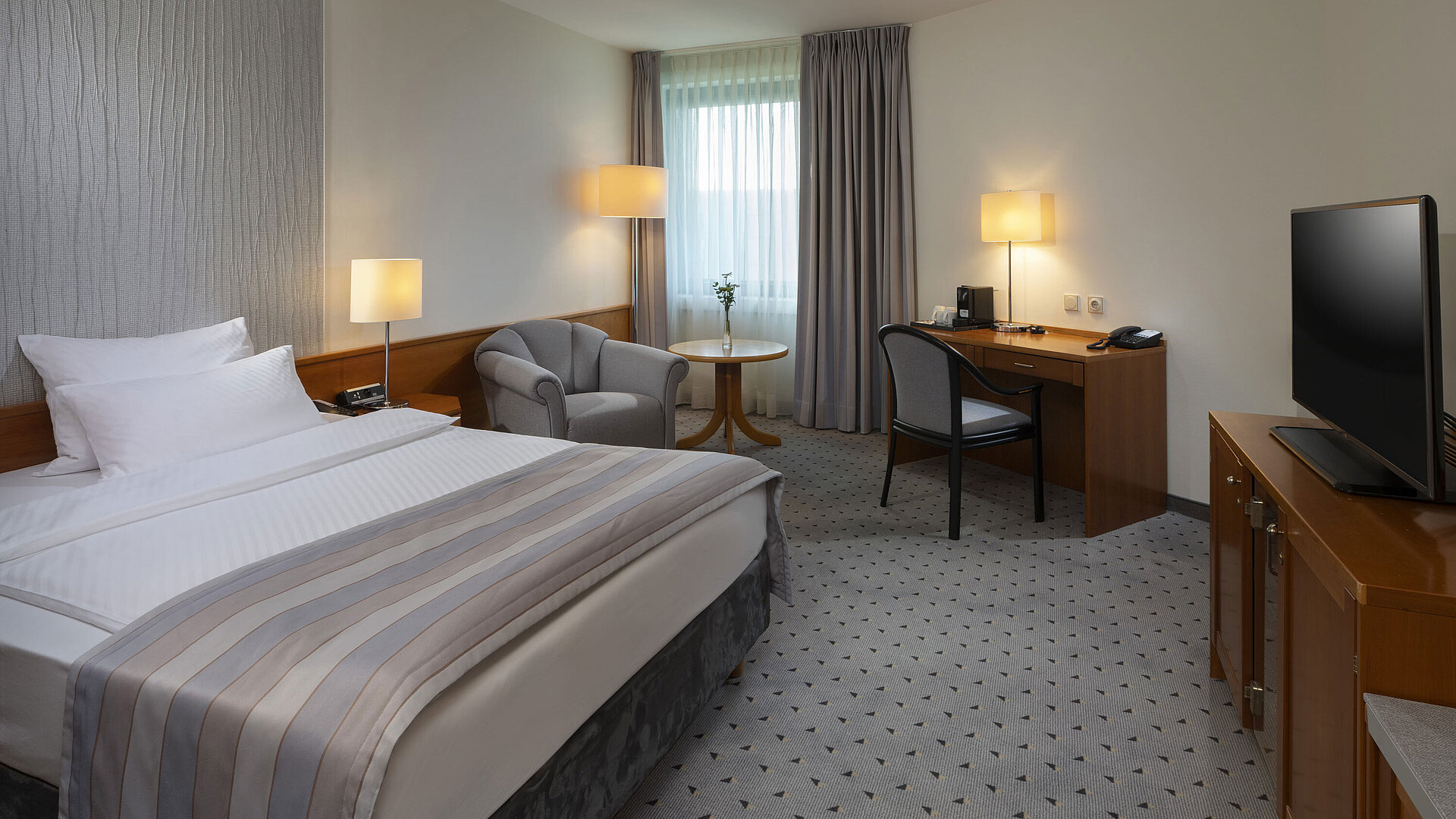 Camera Superior spaziosa con letto, scrivania, TV e illuminazione calda al Maritim Hotel Hannover.