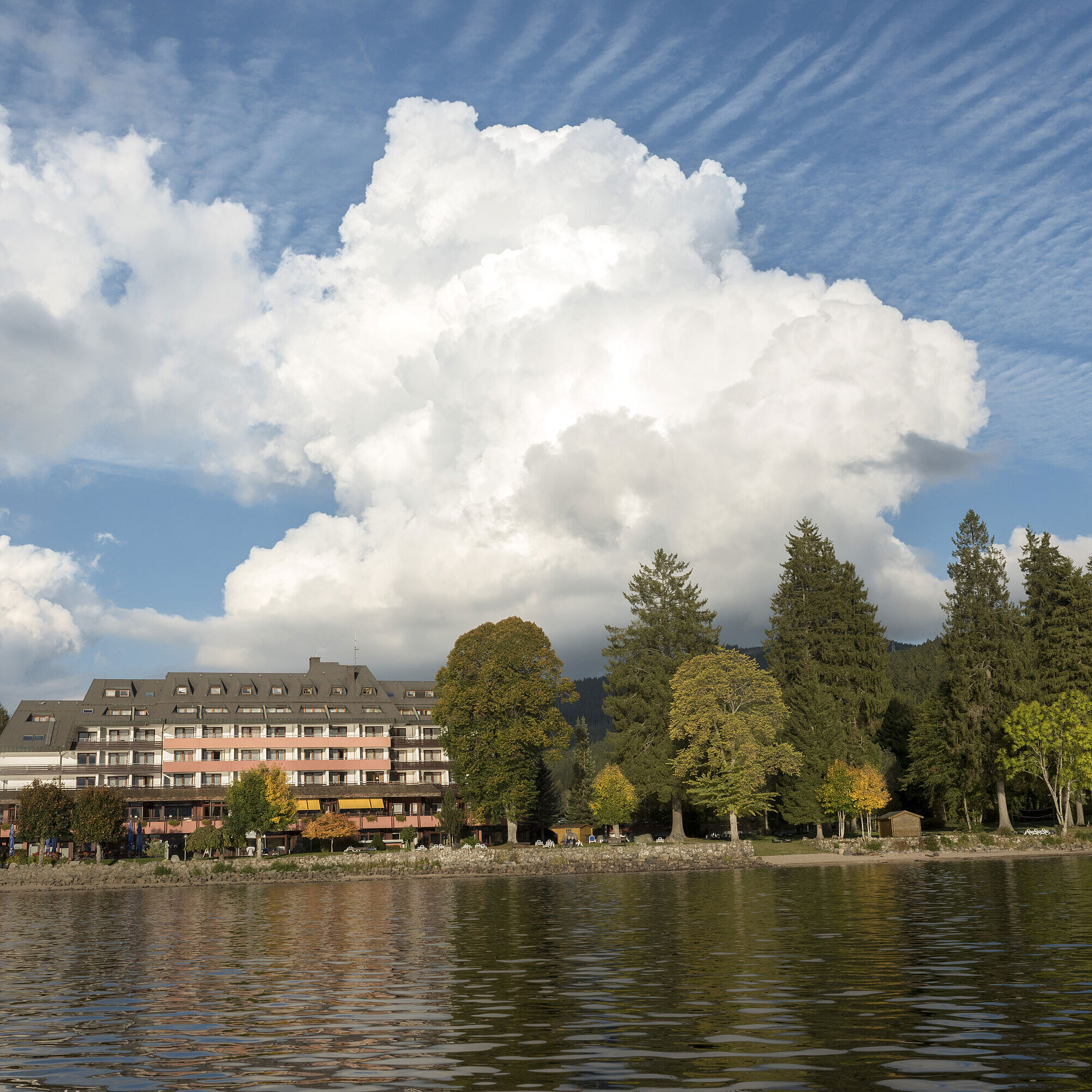 Vue extérieure de l’hôtel Maritim Titisee avec arbres et lac sous un ciel bleu