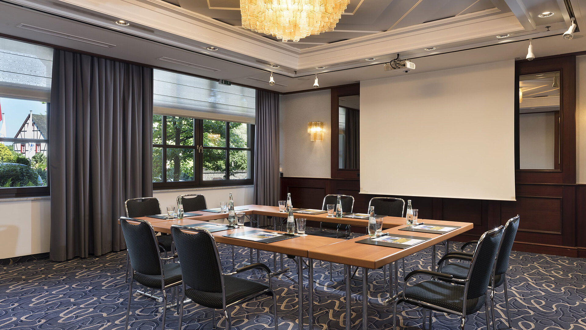 Sala de reuniones luminosa con tecnología moderna, grandes ventanas y lámpara elegante en Maritim Hotel Königswinter.