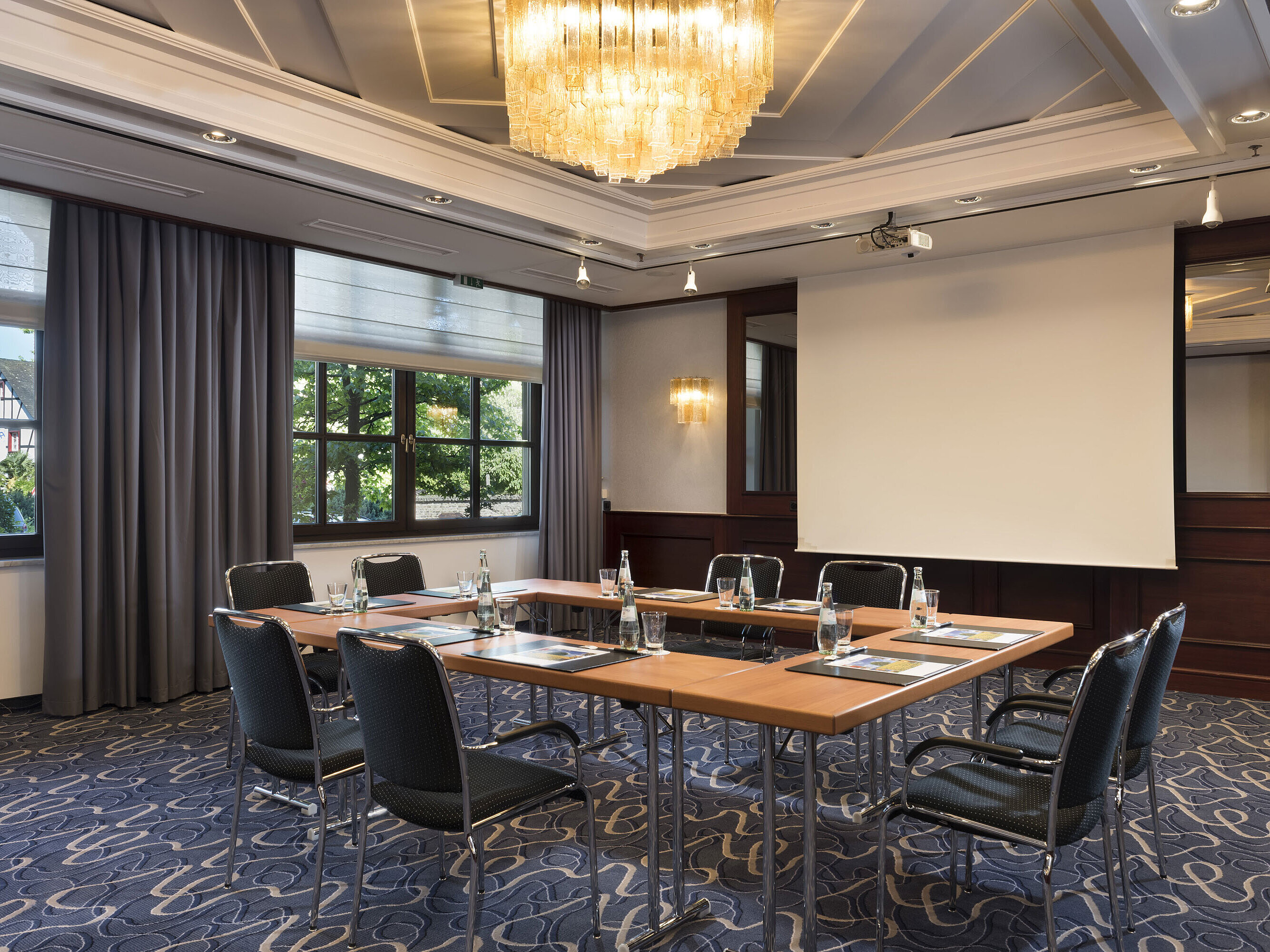 Sala de reuniones luminosa con tecnología moderna, grandes ventanas y lámpara elegante en Maritim Hotel Königswinter.