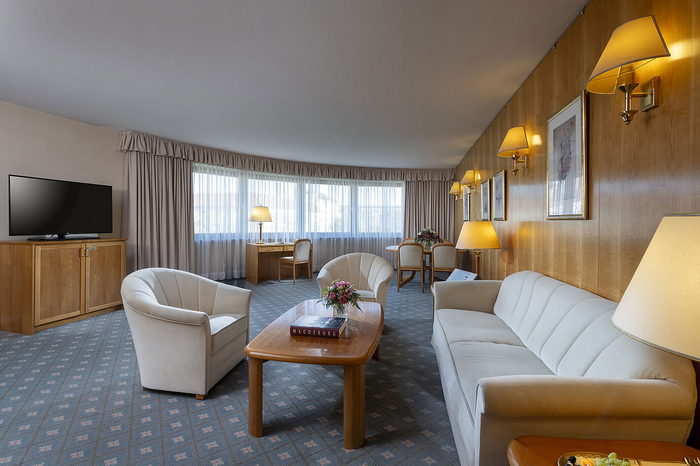Salon spacieux d'une suite au Maritim Hotel Magdeburg avec un mobilier élégant, un coin salon et un espace de travail.