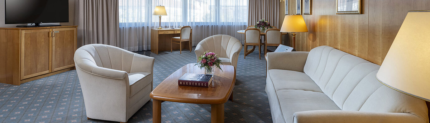 Spacious living room of a suite at the Maritim Hotel Magdeburg with elegant furnishings, seating area, and workspace.