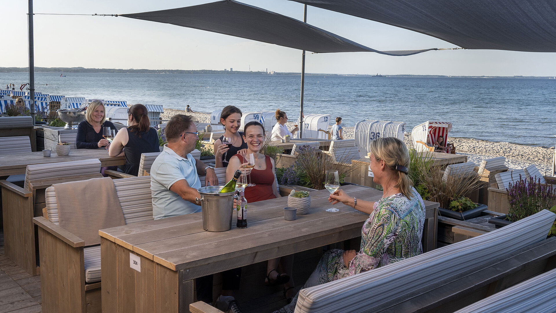 Beach Lounge Gruppo di ospiti al bar sulla spiaggia del Maritim Seehotel Timmendorfer Strand che beve con vista mare e sdraio.