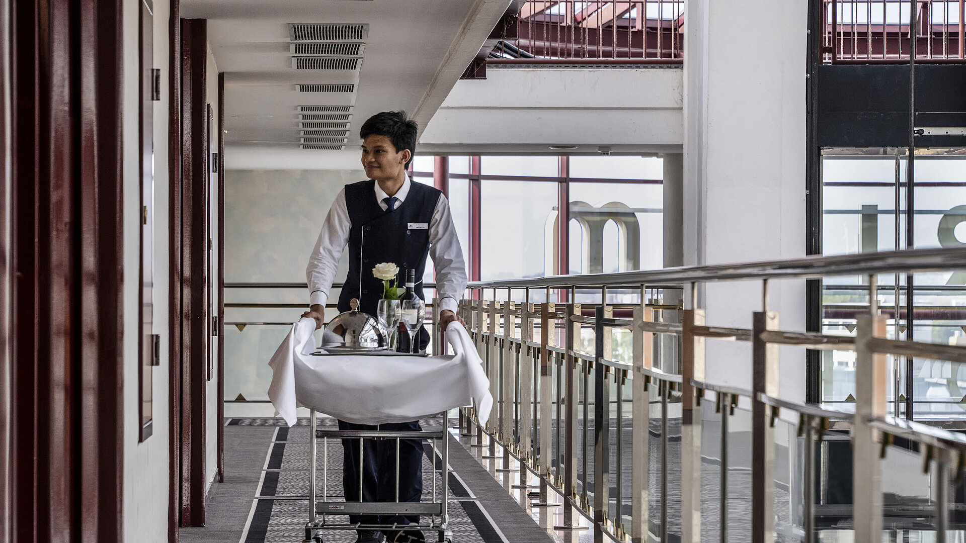 Friendly staff member at the Maritim Hotel Magdeburg providing room service with an elegantly arranged food cart.