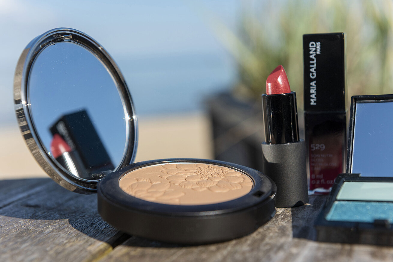 Cosmétiques Gros plan sur des produits de maquillage comme la poudre et le rouge à lèvres de Maria Galland,sur la plage de l'Hôtel Maritim