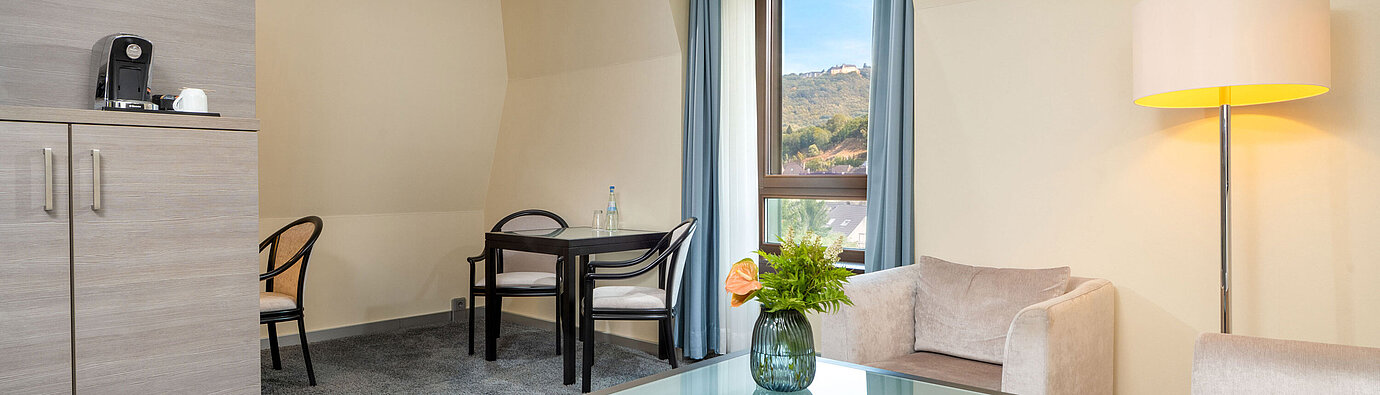 Suite Junior Zona de estar de la Suite Junior del Maritim Hotel Königswinter con asientos, mesa de centro y ventana.