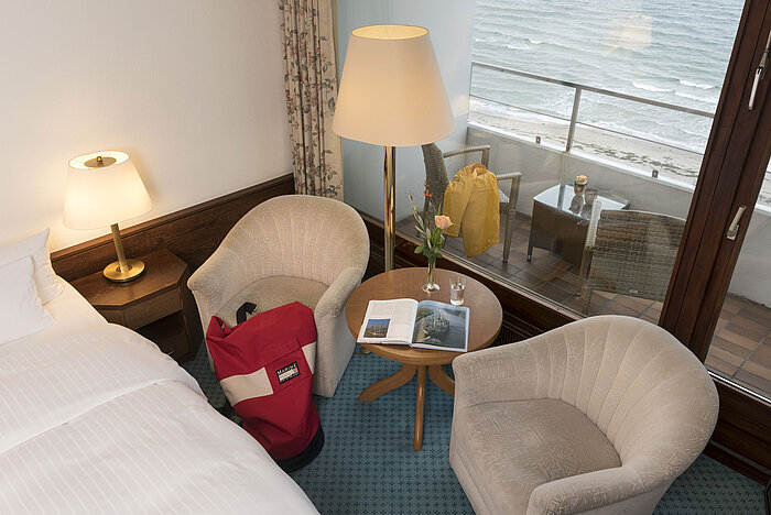 Coin salon avec deux fauteuils, table et vue balcon sur la mer au Maritim Seehotel Timmendorfer Strand.
