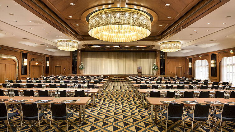 Salle de conférence élégante avec scène, lustres et sièges modernes au Maritim Hotel Königswinter.