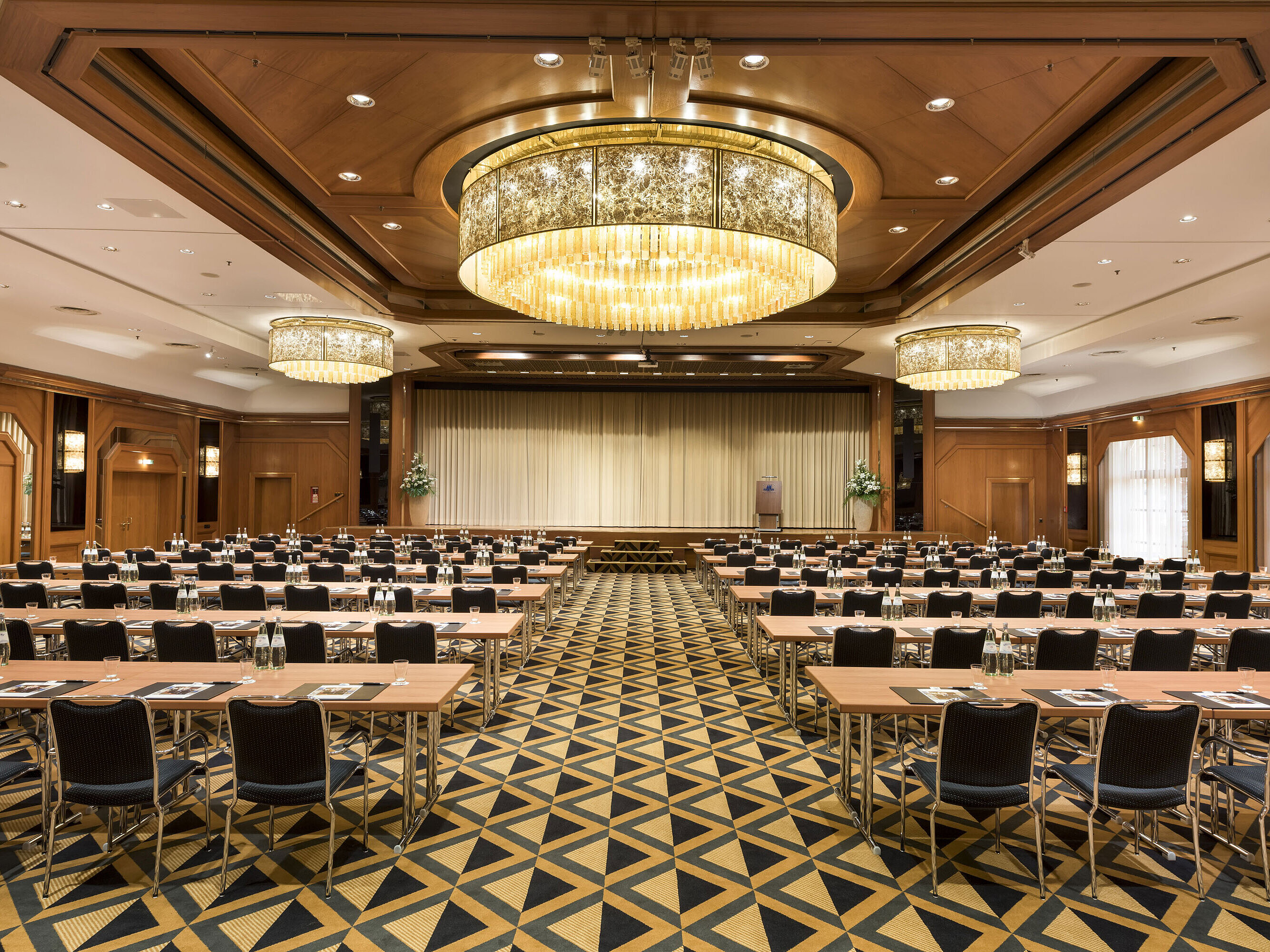 Sala de conferencias elegante con escenario, lámparas y asientos modernos en Maritim Hotel Königswinter.