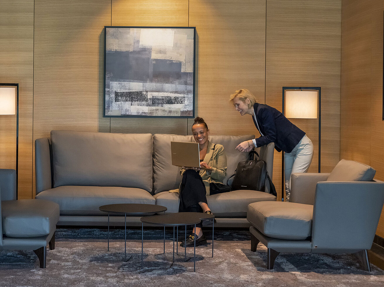 Lounge Two women working in the elegant lounge at Maritim Hotel Ingolstadt with a laptop and modern decor.