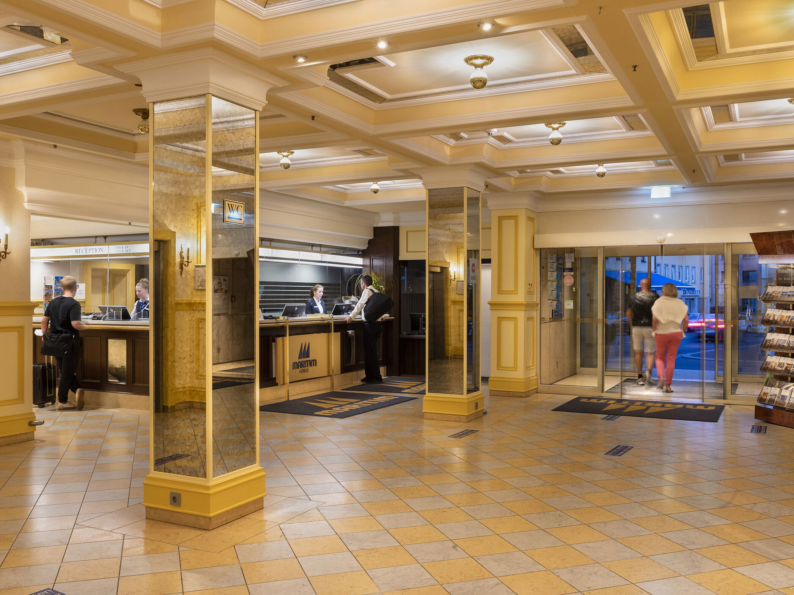 Elegant lobby at Maritim Hotel Würzburg with reception desk, mirrored walls and guests checking in and out