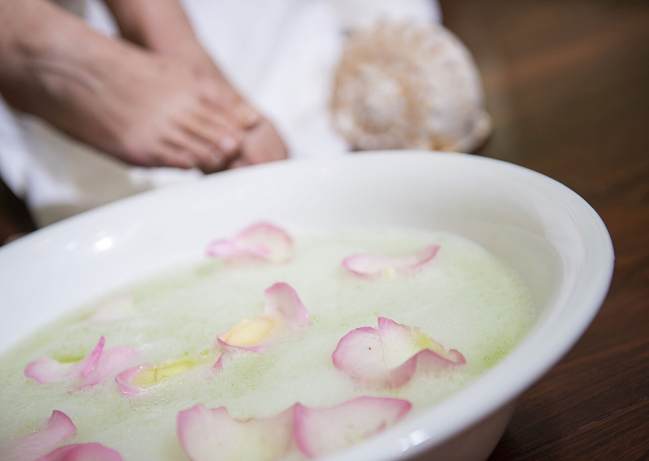 Bain de pieds avec des pétales de rose dans un bol lors d'un soin spa  pour une relaxation et des soins apaisants.