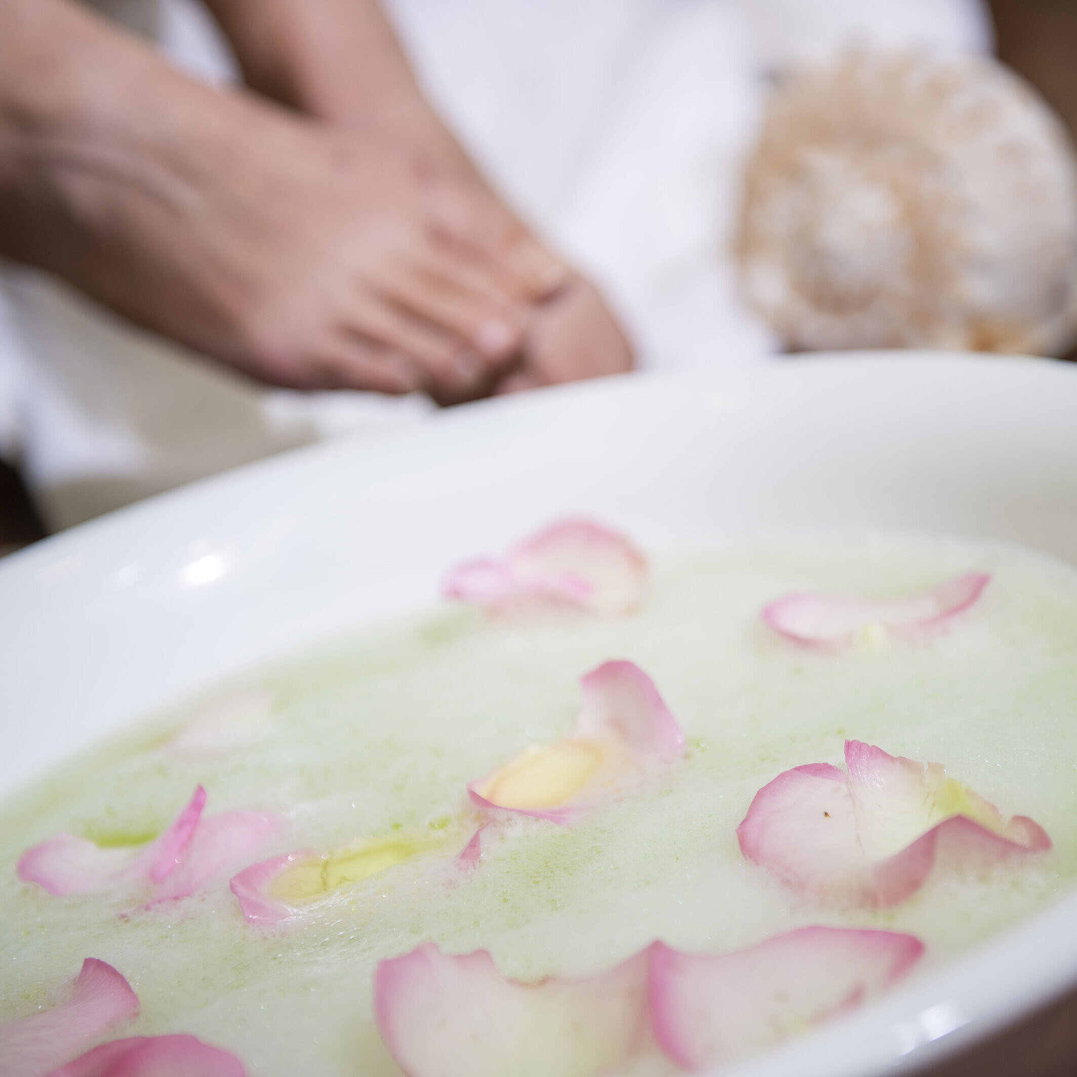 Pediluvio con petali di rosa in una ciotola durante un trattamento spa all'Hotel Maritim per rilassamento e cura.