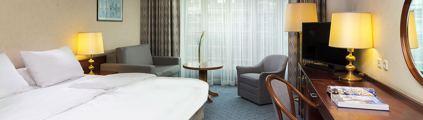 Chambre familiale Chambre familiale lumineuse à l'Hôtel Maritim Cologne avec lit double, bureau, TV, fauteuils et grandes fenêtres avec rideaux