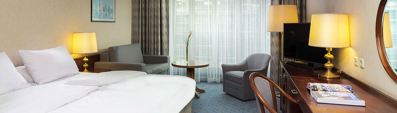 Chambre familiale Chambre familiale lumineuse à l'Hôtel Maritim Cologne avec lit double, bureau, TV, fauteuils et grandes fenêtres avec rideaux