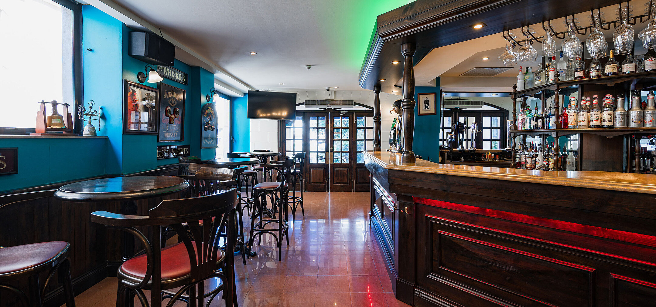Elegante pub-bar del Maritim Antonine Hotel & Spa Malta con interni in legno scuro, selezione di liquori e accoglienti aree salotto.