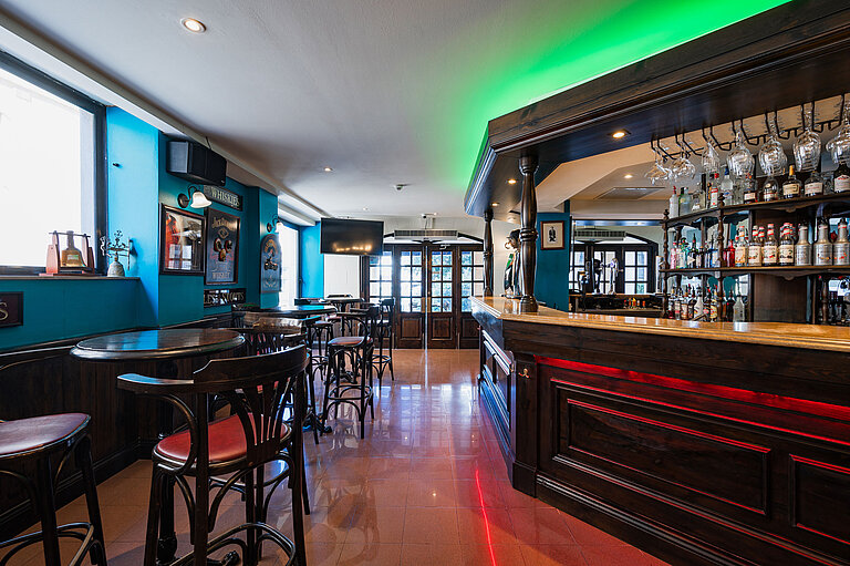 Stylish pub bar at Maritim Antonine Hotel & Spa Malta featuring dark wood interiors, a selection of spirits and cosy seating areas.