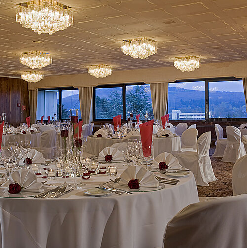 Amplio salón con mesas redondas y decoración elegante en Maritim Hotel Bad Salzuflen