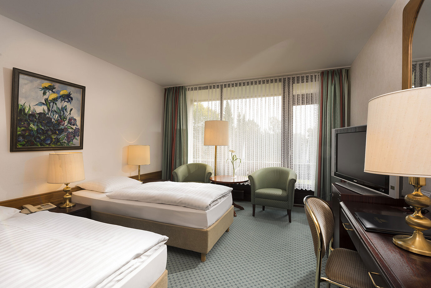Chambre avec deux lits, fauteuils et balcon à l’hôtel Maritim Bad Salzuflen