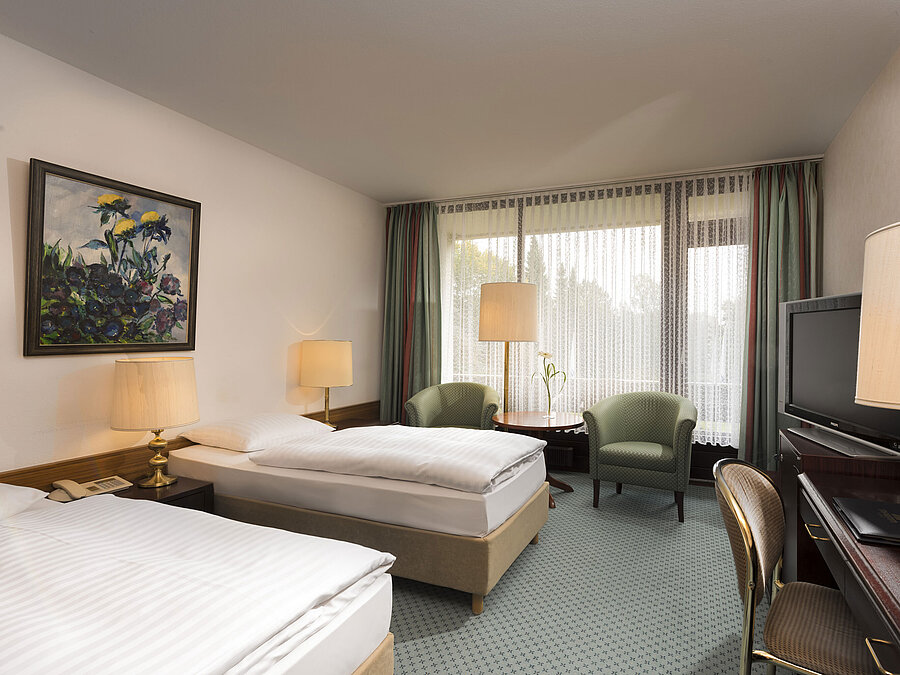 Dos camas, sillones y balcón en el Maritim Hotel Bad Salzuflen