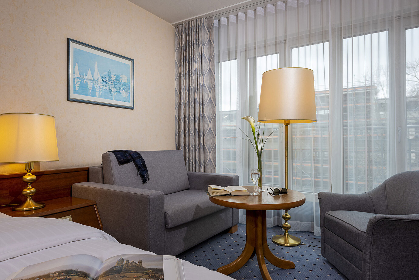 Camera comfort del Maritim Hotel Köln, con accogliente area salotto, tavolo da lettura e arredi moderni.