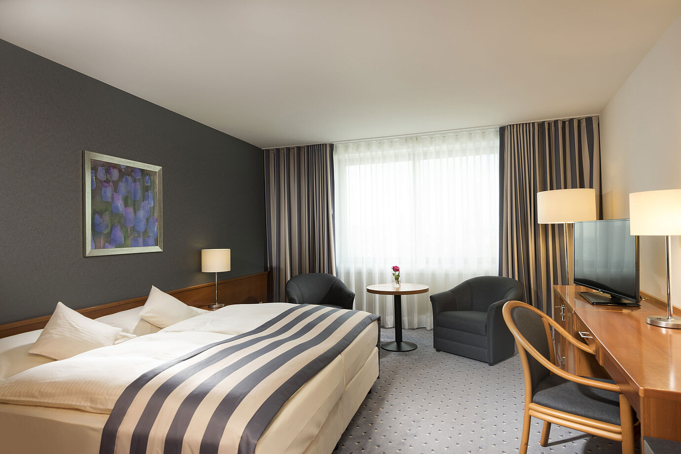 Ampia camera doppia al Maritim Hotel Ulm con luce naturale e zona salotto