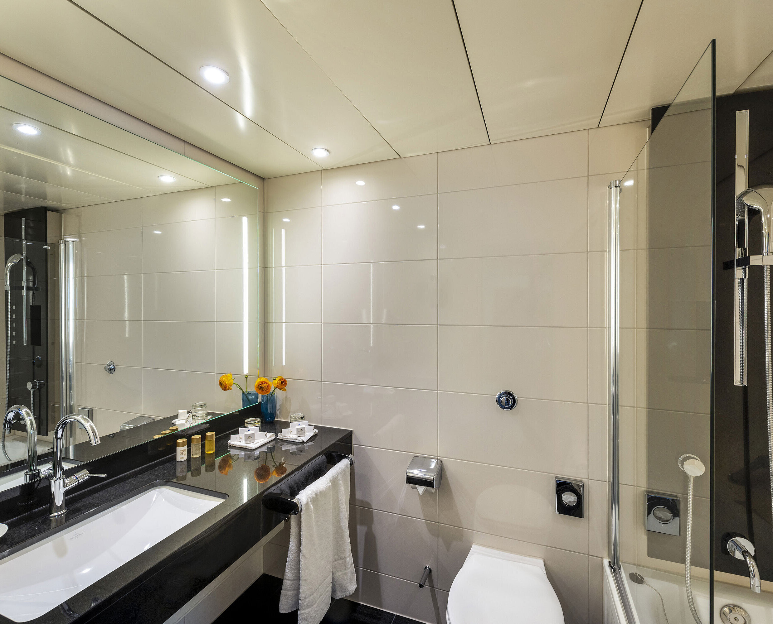 Bagno con vasca Bagno moderno con vasca da bagno, grande specchio, rubinetteria elegante e comfort di alta qualità presso il Maritim Hotel Ulm.