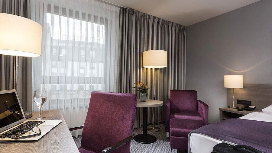 Chambre simple élégante de l'hôtel Maritim Königswinter avec bureau, fauteuil et design moderne.