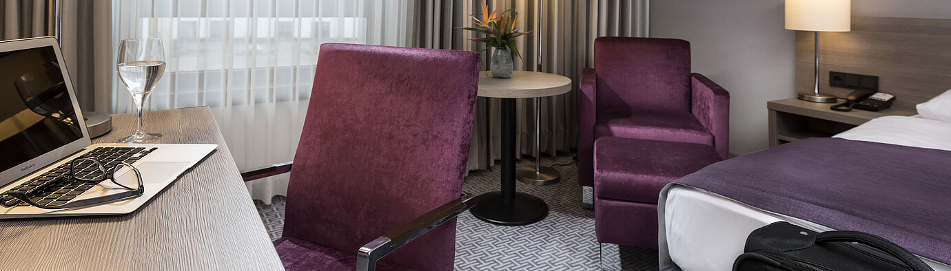 Chambre simple élégante de l'hôtel Maritim Königswinter avec bureau, fauteuil et design moderne.