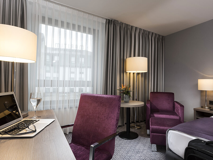 Habitación individual elegante del Maritim Hotel Königswinter con escritorio, sillón y diseño moderno.