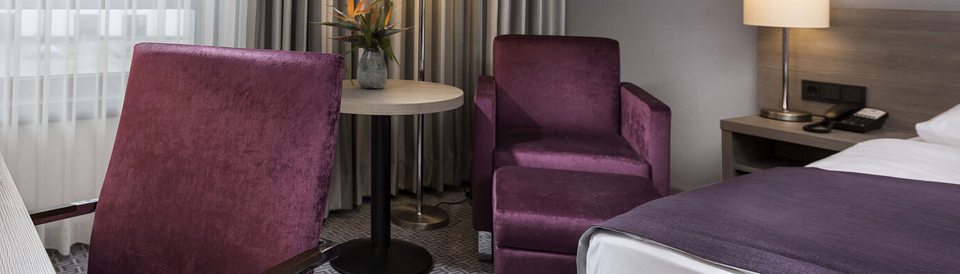 Chambre simple élégante de l'hôtel Maritim Königswinter avec bureau, fauteuil et design moderne.