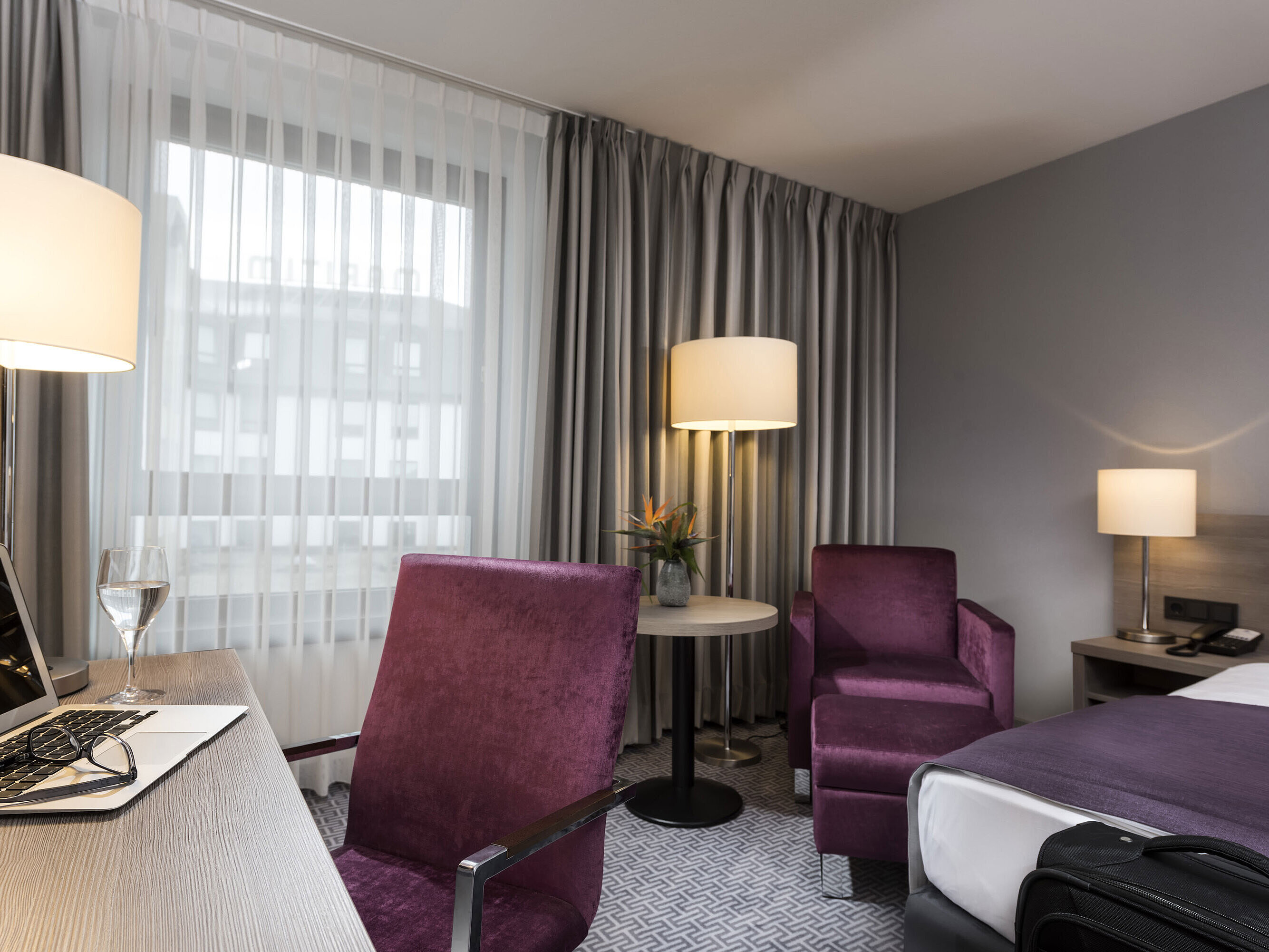 Chambre simple élégante de l'hôtel Maritim Königswinter avec bureau, fauteuil et design moderne.