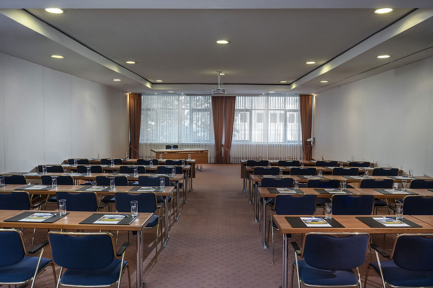 Sala de reuniones moderna en el Maritim Hotel Magdeburg con asientos en fila, luz natural y equipamiento técnico.