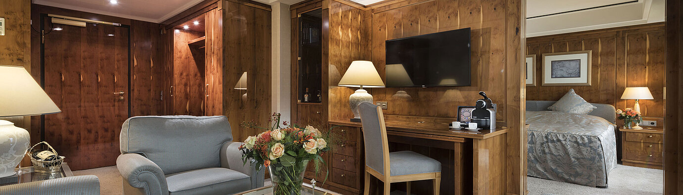 Suite penthouse avec salon, meubles en bois, bureau et vue sur la chambre au Maritim Seehotel Timmendorfer Strand.