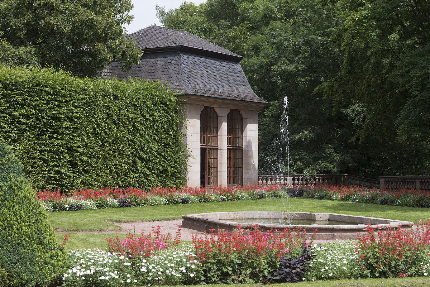 Pabellón histórico en el jardín florecido del Maritim Hotel Fulda con fuente y juegos de agua.