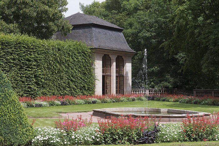 Pabellón histórico en el jardín florecido del Maritim Hotel Fulda con fuente y juegos de agua.