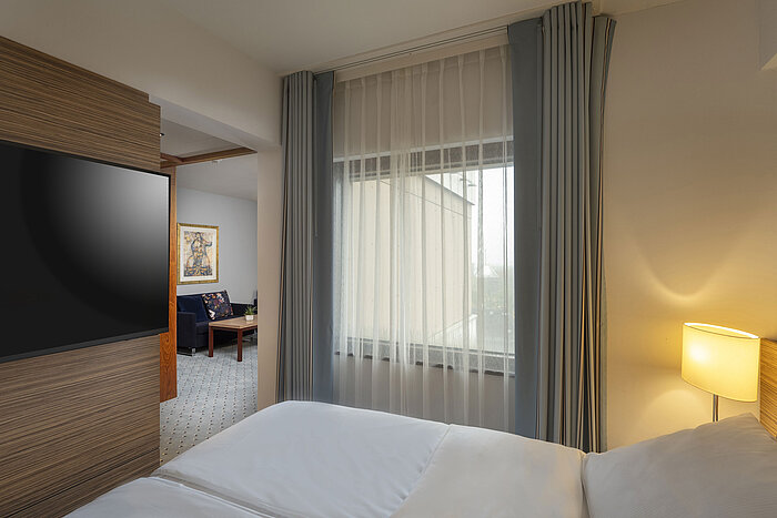 Junior suite at the Maritim Hotel Darmstadt with cozy bed,separate living area, and floor-to-ceiling window for natural light