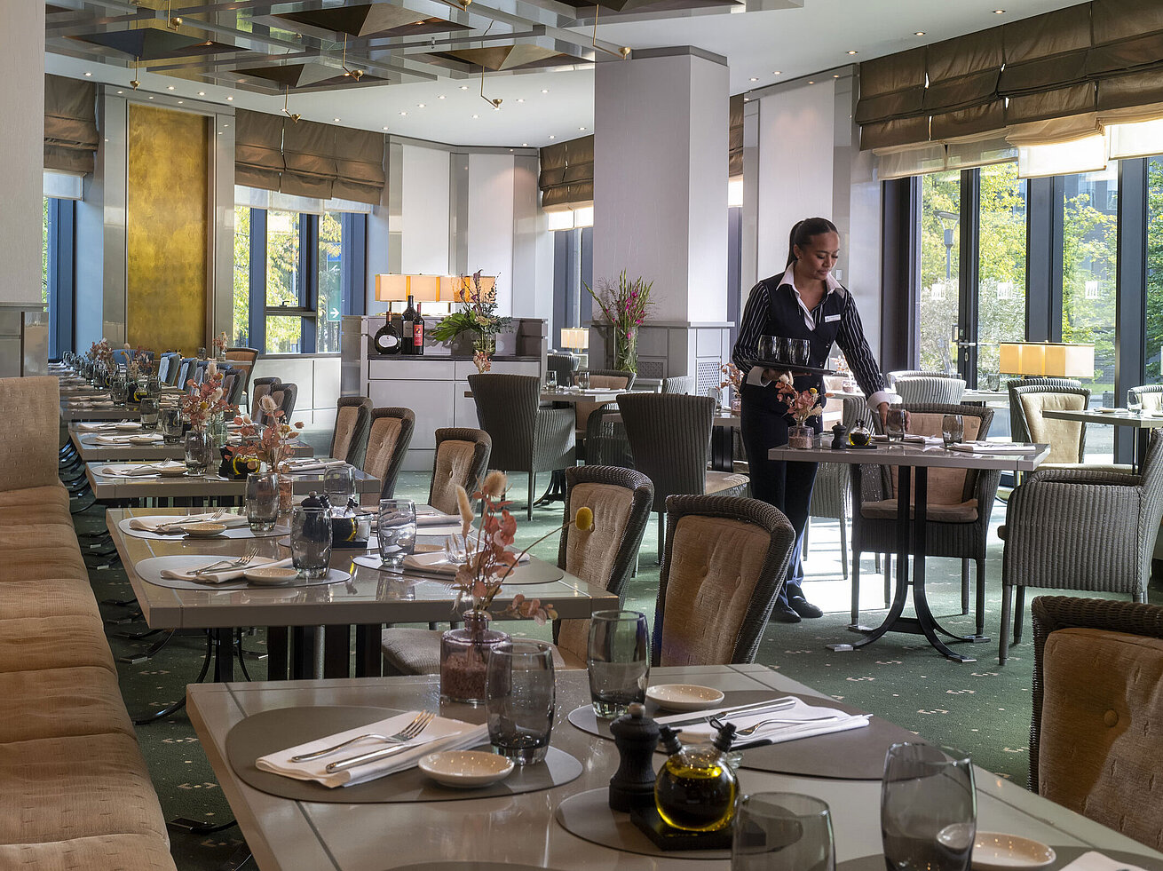 Stylish restaurant at Maritim Hotel Düsseldorf with set tables and a waitress.