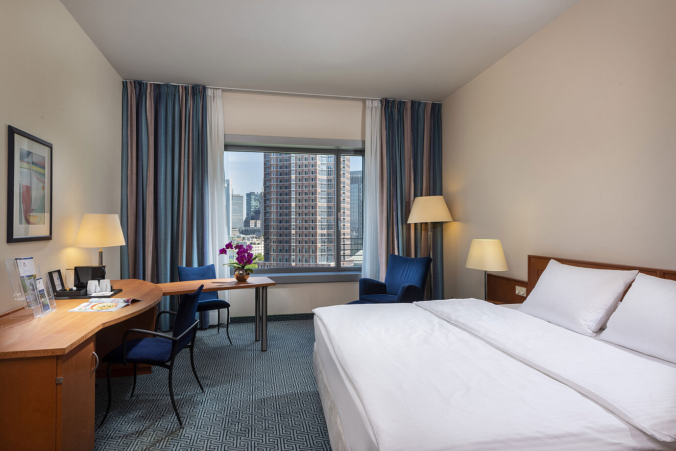 Camera Superior del Maritim Hotel Frankfurt con letto matrimoniale, scrivania e vista sullo skyline di Francoforte.