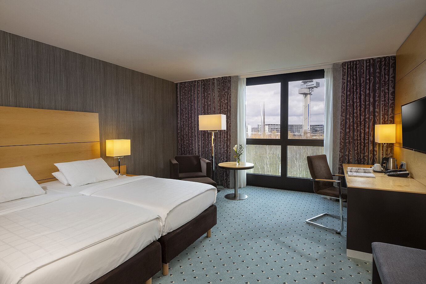 Chambre classique au Maritim Hotel Düsseldorf avec lit double, bureau et fenêtre panoramique avec vue sur les environs.
