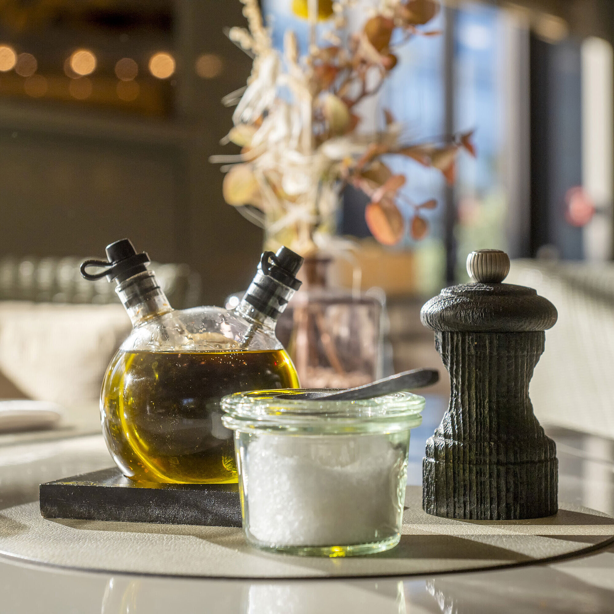 Détail du restaurant Gros plan sur une table dressée au Maritim Hotel Düsseldorf avec huile d'olive, sel et moulin à poivre.