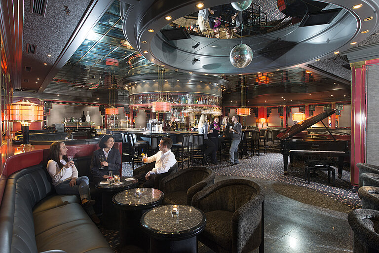 Guests enjoy cocktails in the stylish bar with a piano and elegant lighting at Maritim Hotel Hannover.