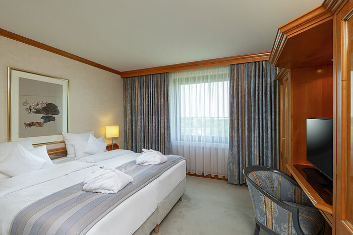 Camera doppia luminosa al Maritim Hotel Hannover con letto accogliente e scrivania.