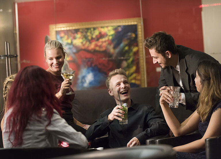 Groupe de clients profitant de cocktails et riant au bar de l’hôtel Maritim proArte Berlin.