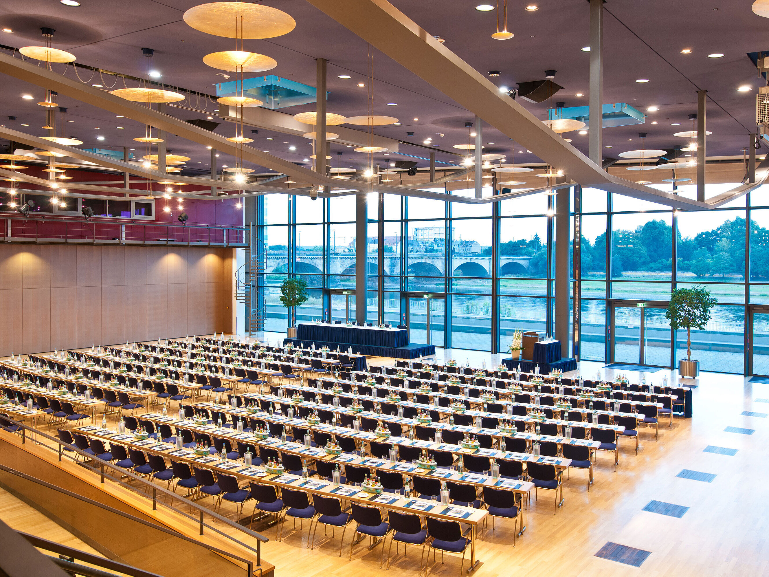 Gran sala de conferencias del Maritim Hotel Dresde con filas de sillas azules y vista al río Elba.